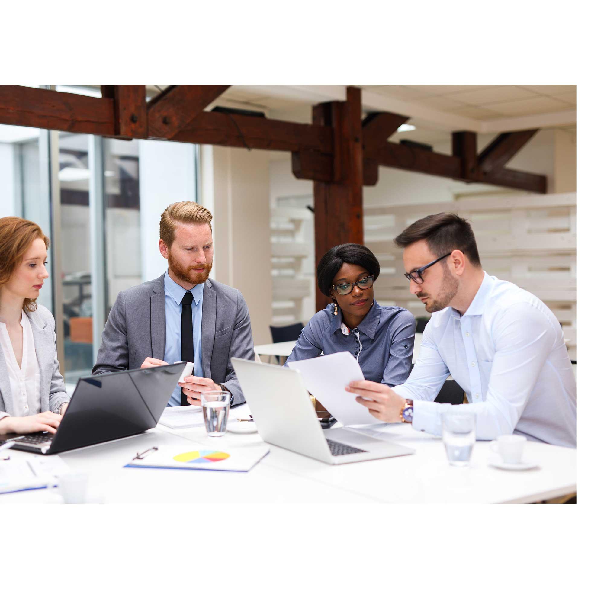 Administrators sitting at a table with laptops learning how to use CentralSquare Enterprise Asset Software